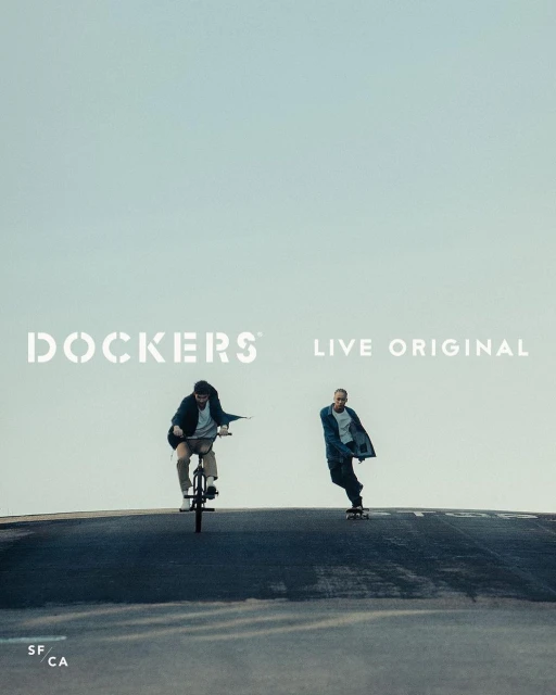 Two people on a street, one rides a BMX bike, and the other rides a skateboard, with the Dockers logo above them. 
