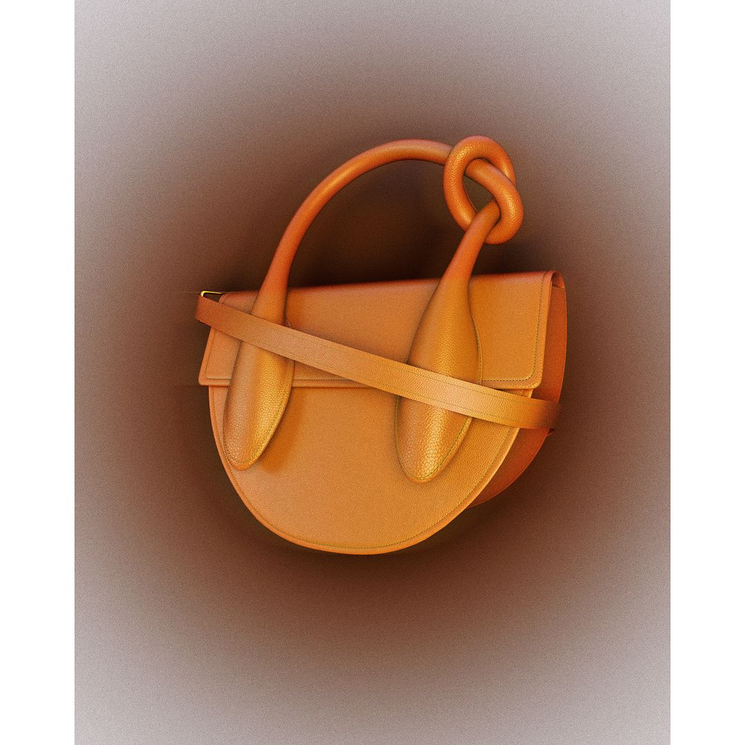 Studio shot of a contemporary saddlebag purse in tan leather with a sculptural handle on a neutral-toned background.