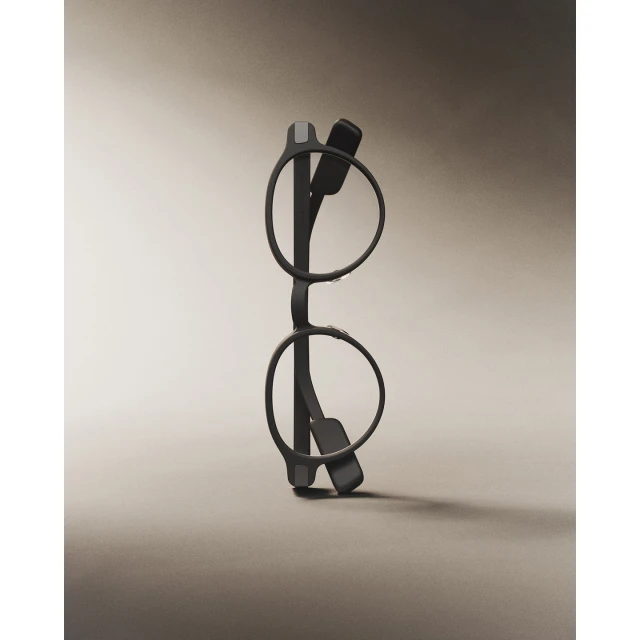 Studio shot of gray eyeglasses, displayed upright. The lighting highlights the sleek design and matte texture against a gradient background.