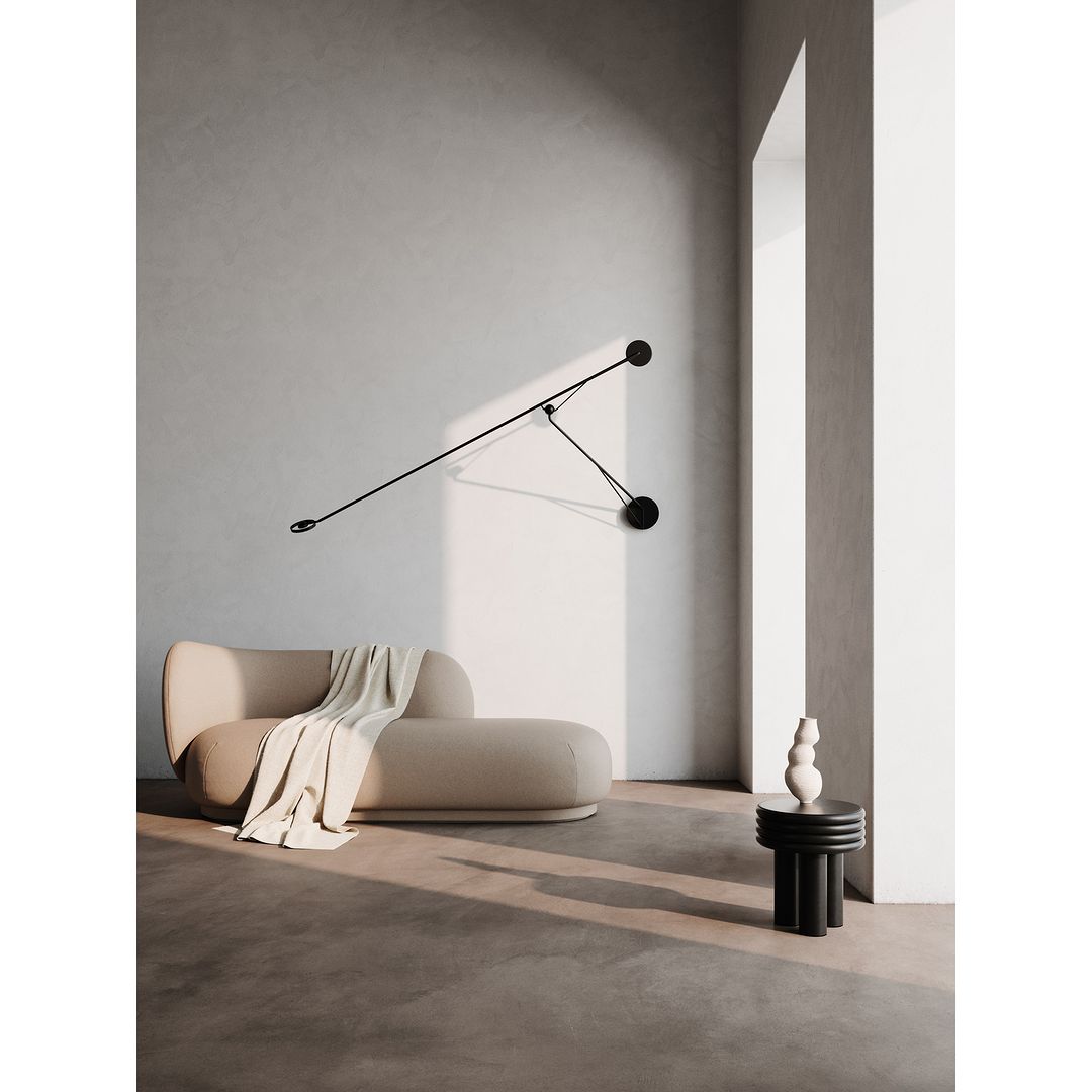 Interior featuring a beige sofa with a white throw, a black side table with vases, and a modern black articulating wall lamp.