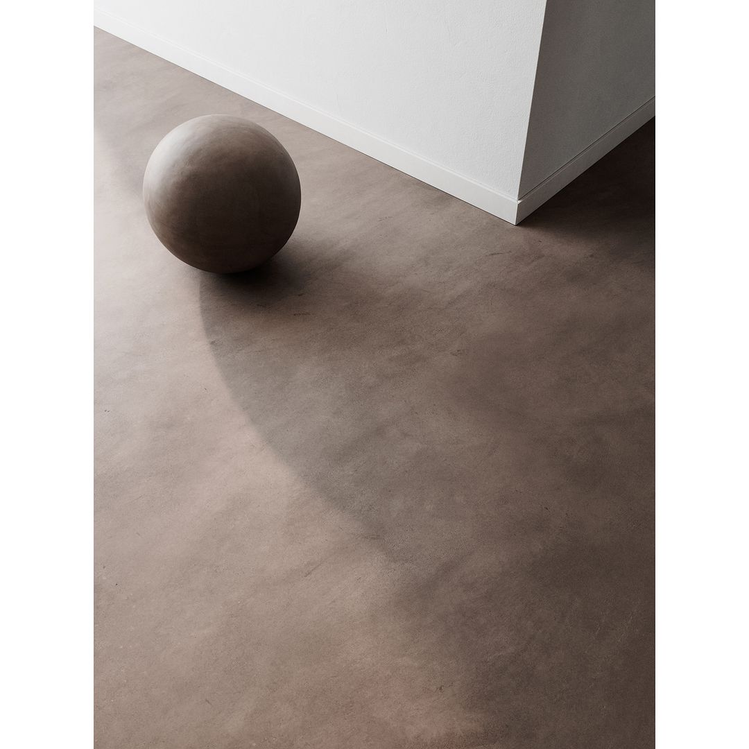 Minimalist interior scene featuring a brown sphere sitting on a light brown floor against a white wall, creating a clean, modern aesthetic.