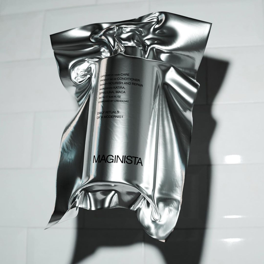 Product shot of a silver foil-wrapped bottle of Maginista hair care product against a white tiled wall with soft, diffused lighting.