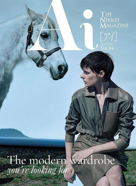 Fashion magazine cover featuring a model in green outfit next to a white horse against a light blue backdrop with text overlays.