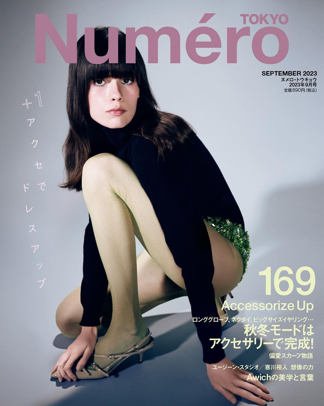 Fashion magazine cover featuring a model in a black turtleneck and green sequin shorts, posed against a light grey background.