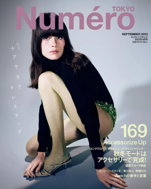 Fashion magazine cover featuring a model in a black turtleneck and green sequin shorts, posed against a light grey background.