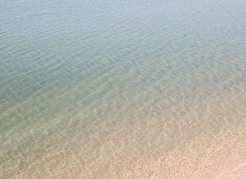 Shallow turquoise water meets a sandy beach in a serene, sun-drenched coastal landscape, perfect for backgrounds or travel themes.