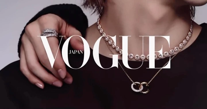 Close-up portrait of a person wearing a diamond necklace and rings, with large Vogue Japan text across the image.