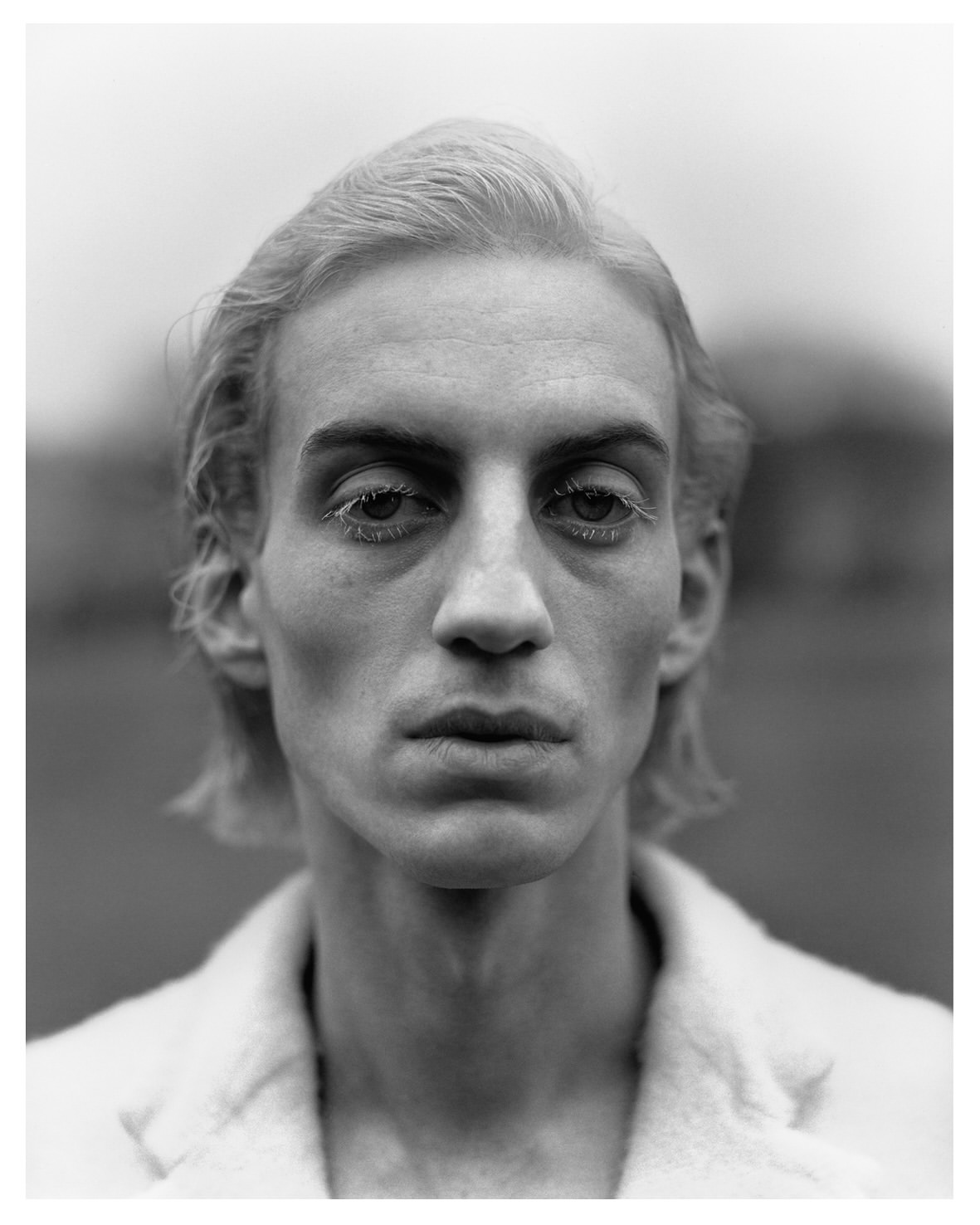 Monochrome portrait of adult male with light hair wearing a bright coat. Close up of a person staring directly at the camera.