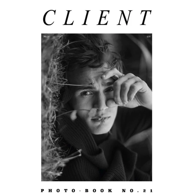 Black and white portrait of a young adult male on the cover of CLIENT photobook no. 21, with dominant text and natural background.