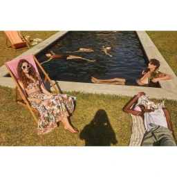 Group of people relaxing by an outdoor swimming pool on a sunny day photographed by Sergi Pons.