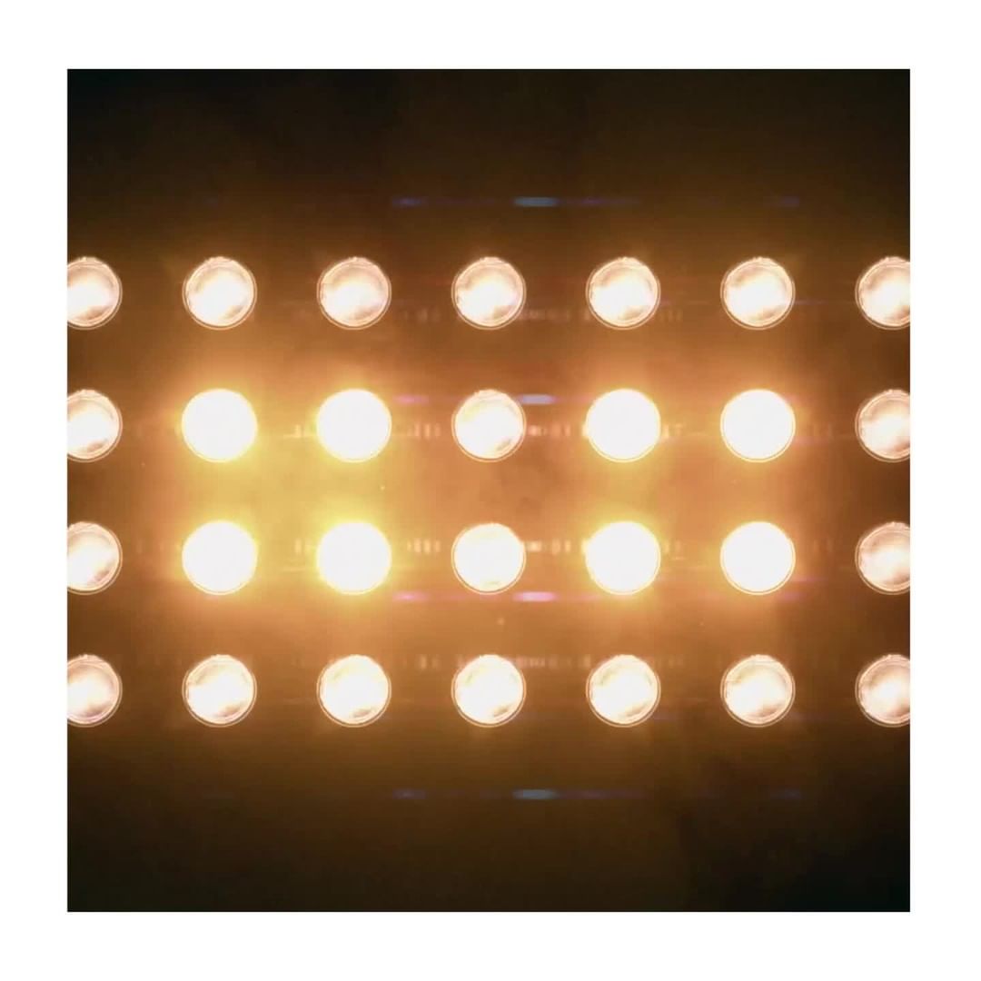 Rows of stage lighting illuminate a dark background, creating a symmetrical, textured pattern of light and shadow. Concert stage lights.