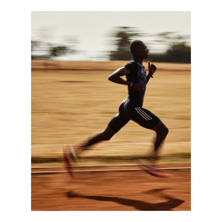 Action shot of a black male athlete running on a track outdoors, showcasing motion blur and dynamic composition. Fitness and sport concept.