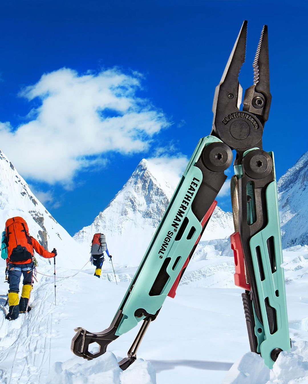 Leatherman Signal multi-tool standing in snowy mountain environment with hikers in the background against a blue sky with clouds.