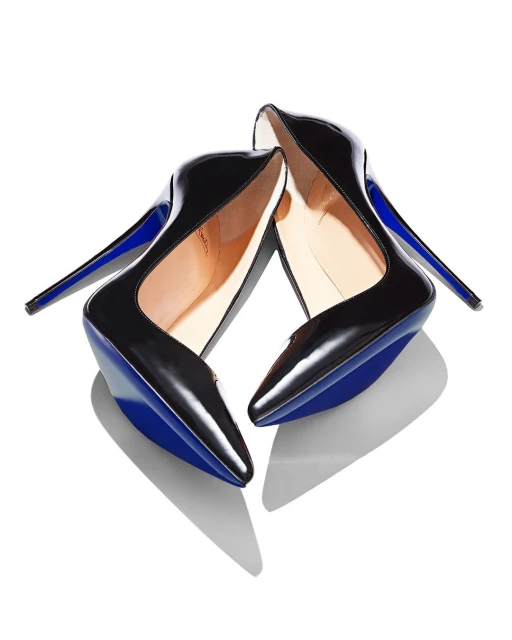 Pair of shiny black patent leather stiletto high-heeled shoes with a blue sole and stiletto heel on a white background, casting shadows.