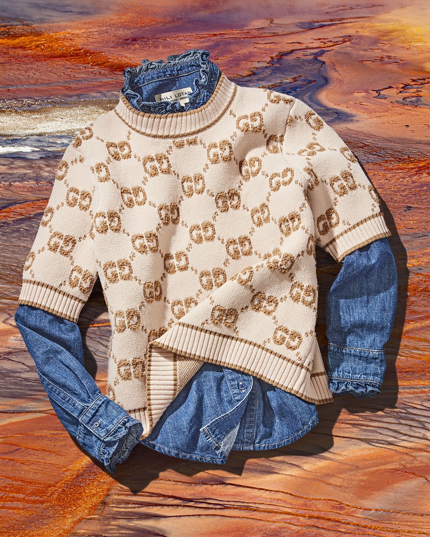 Beige monogram knit sweater layered over a blue denim shirt against an abstract geological background photograph by Shana Novak.