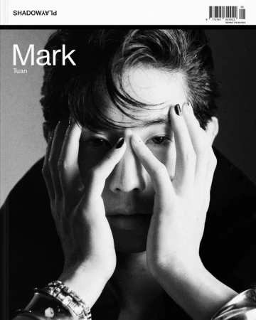 Portrait of Mark Tuan with hands framing his face, featuring dark nail polish and chunky silver bracelets