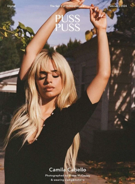 Camila Cabello on magazine cover with arms raised against an outdoor setting, featuring natural light and a casual fashion style.