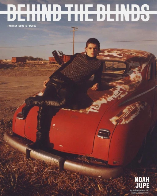 Magazine cover featuring a young man reclining on a vintage red car in a desert setting, highlighting fashion and automotive elements.