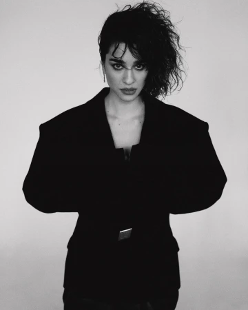 Portrait of a woman wearing an oversized black structured blazer against a plain white background by Shane Mccauley