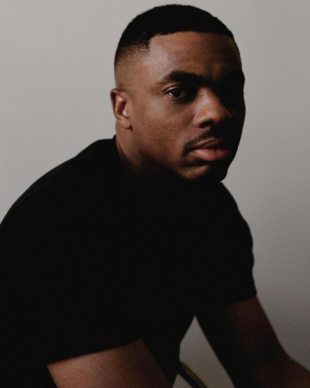 Portrait of a Black man wearing a black t-shirt against a plain studio background by Shaniqwa Jarvis.