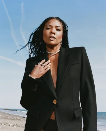 Gabrielle Union in a black blazer on a sandy beach under a clear blue sky, photographed by Shaniqwa Jarvis.