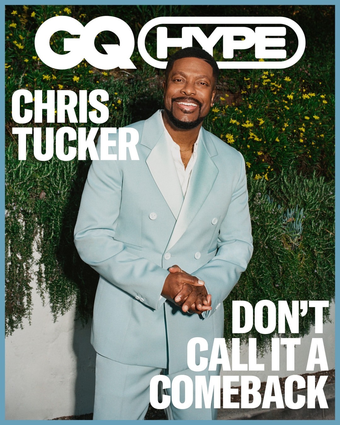 Chris Tucker in a light blue suit poses on the cover of GQ Hype magazine in front of leafy green foliage. He's smiling and looking forward.