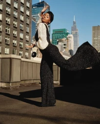 Woman in sparkly black jumpsuit with white sleeves posing on a rooftop in New York photographed by Shaniqwa Jarvis