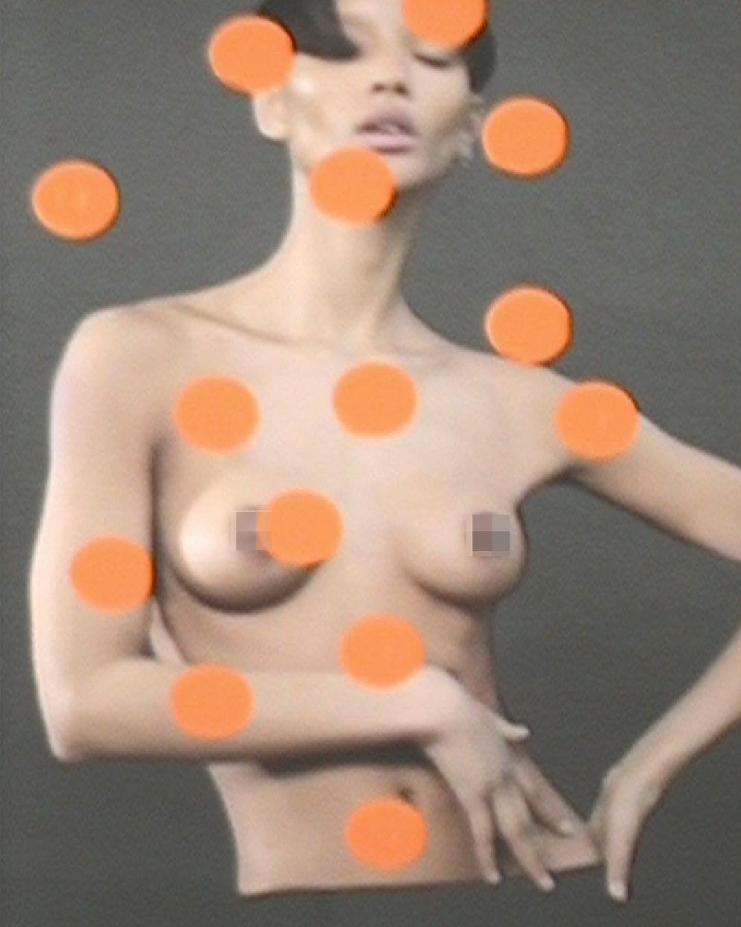 Nude adult female portrait featuring short dark hair, a bare torso, and a neutral expression, partially obscured by bright orange dots.