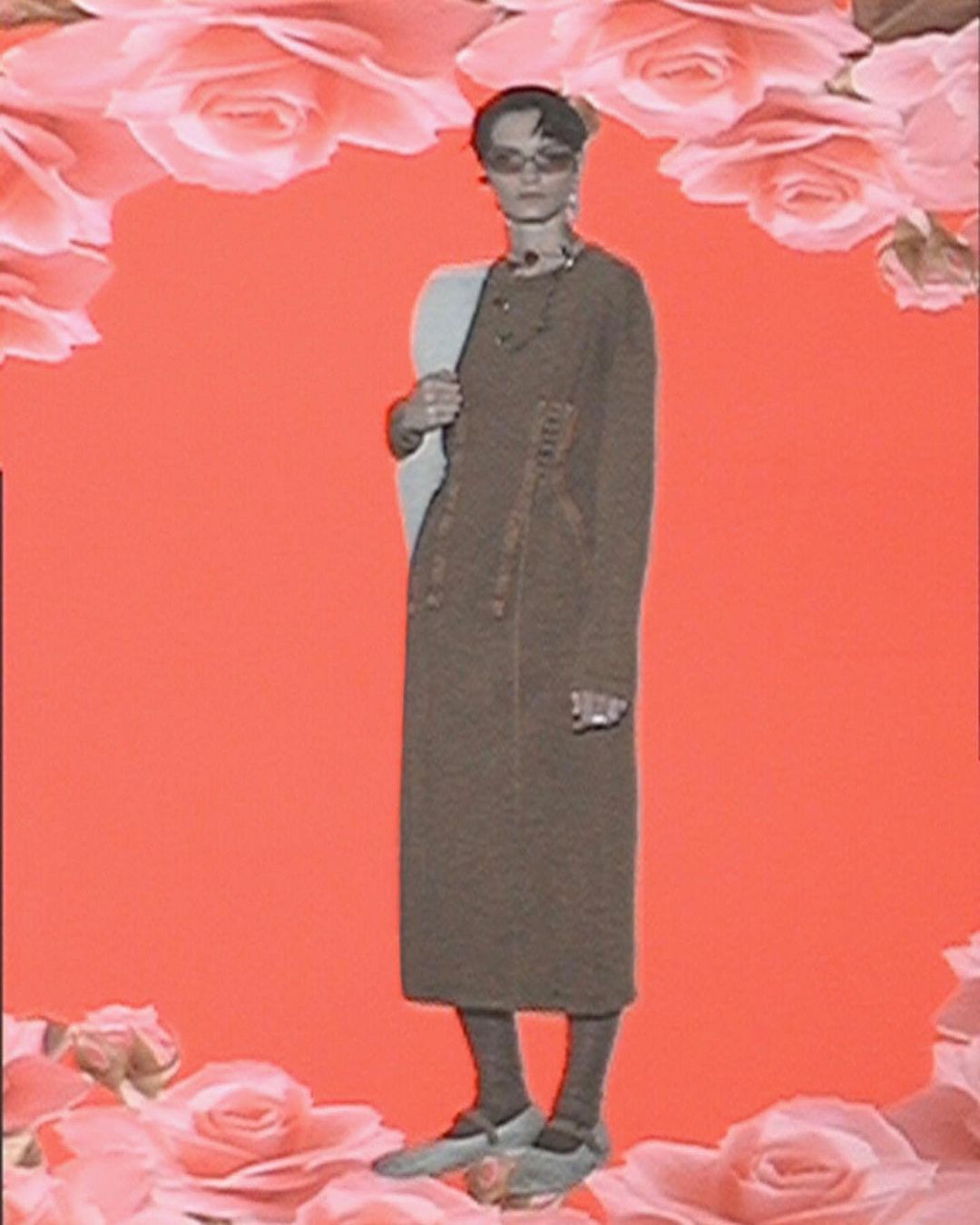 Full-length shot of a female model in a brown dress and flats, standing in front of an orange backdrop with roses, in a fashion editorial.