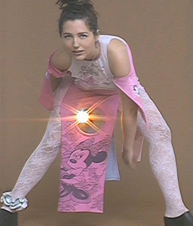 Young adult woman in a playful pose, wearing a customized dress with a cartoon character graphic and lace tights against a neutral backdrop.