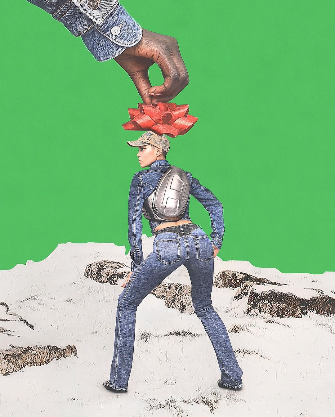 Woman in all-denim outfit stands on a landscape with a red bow above her head, manipulated by a dark-skinned hand, against a green screen.