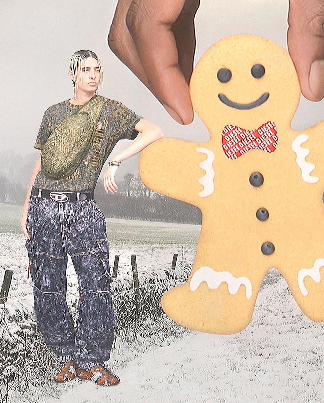 Woman in patterned shirt and pants with a Diesel belt stands in a snowy field holding a gingerbread man cookie with a Diesel bowtie.