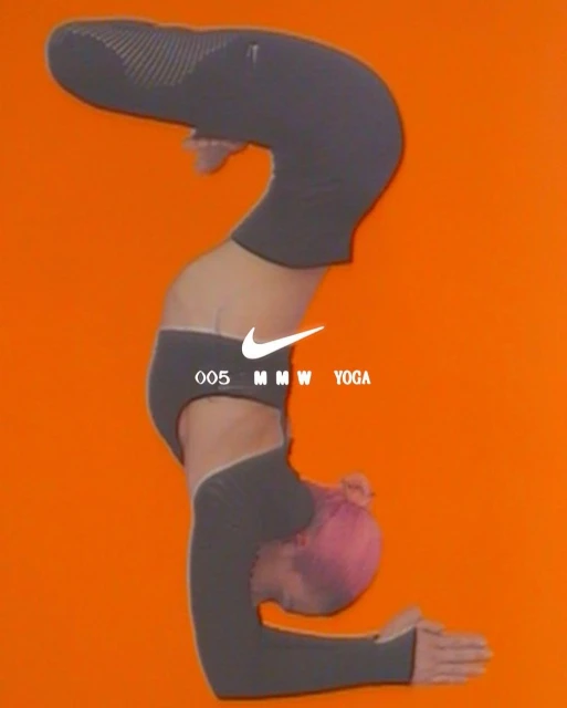 Person with pink hair in yoga pose against orange background, wearing gray workout clothes. Nike and MMW Yoga logo at center.