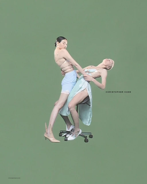 Two women in contemporary fashion pose on an office chair against a green background in a studio shot for a fashion editorial.