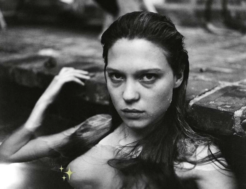 Black and white portrait of a woman in water, close up shot.  The woman has long dark hair and is partially submerged in the water.
