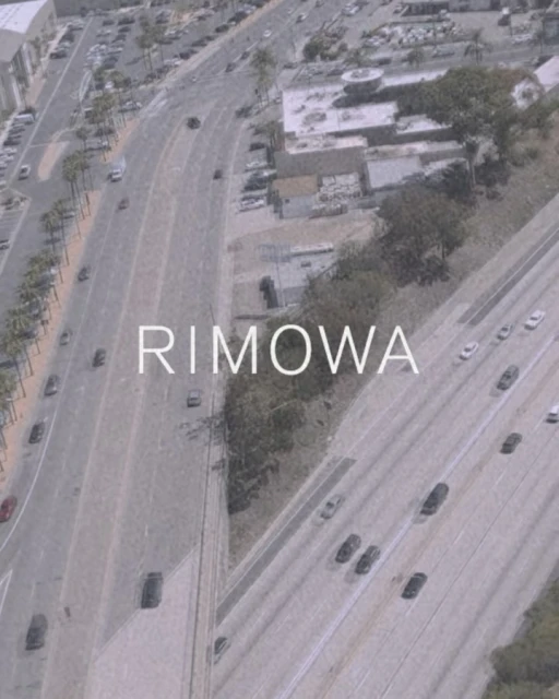 Aerial view of a multi-lane highway with cars and infrastructure during daytime, featuring the text "RIMOWA" overlaid on the image.