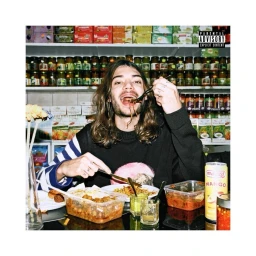 Man with long brown hair eating food with fork in a grocery store setting photographed by Shelby Duncan