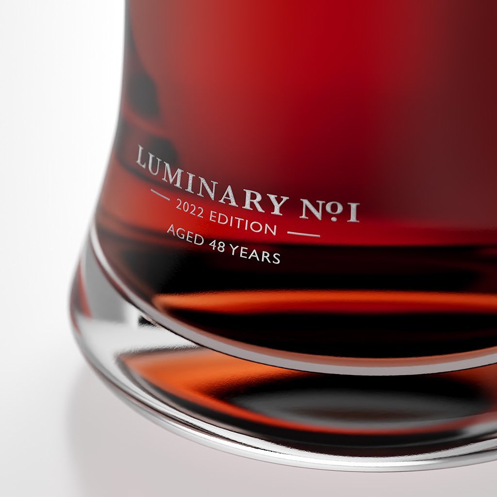 Close-up of a dark red spirit inside a clear glass bottle with reflective silver base and product text Luminary No. 1 2022.