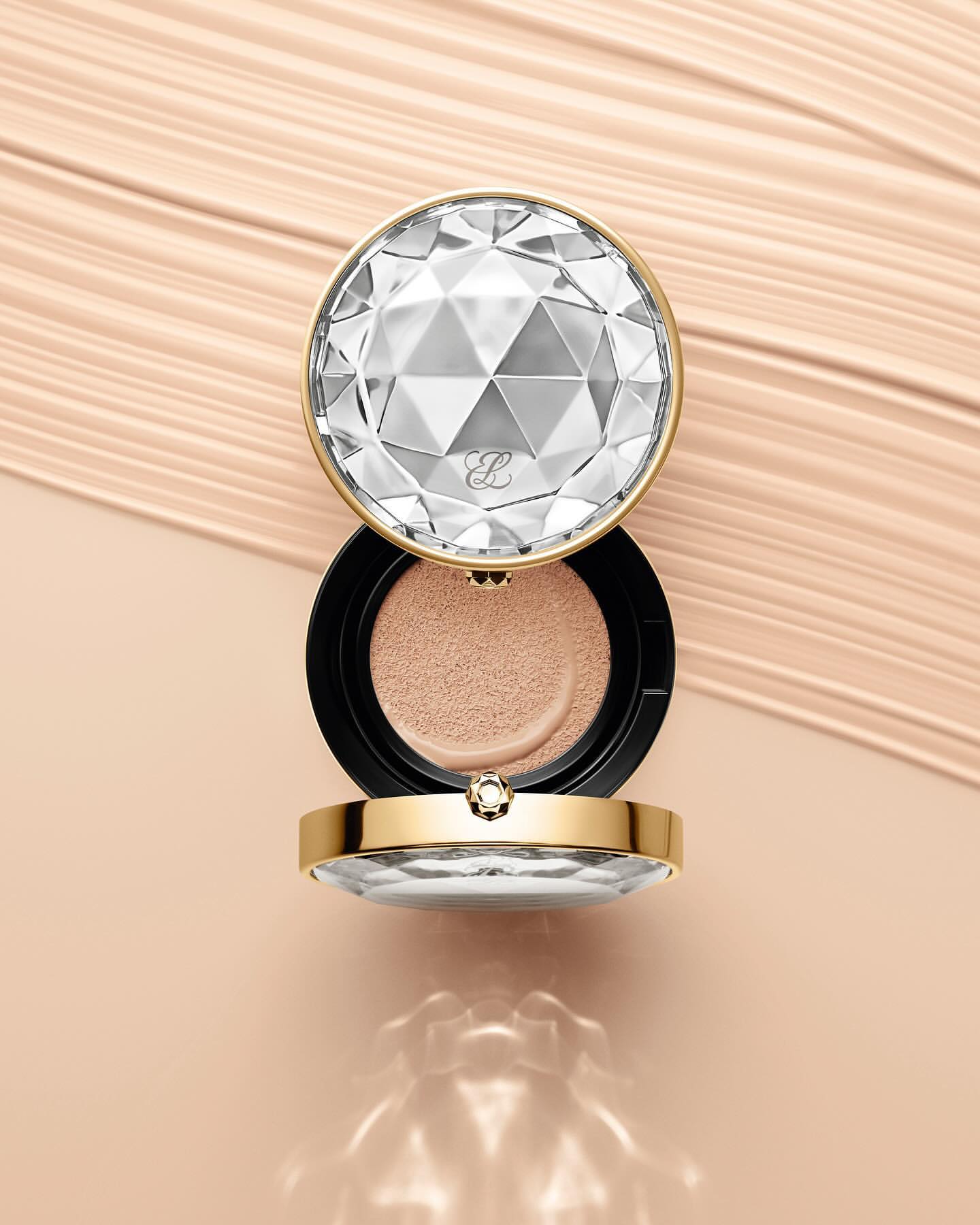 Elegant makeup compact featuring a faceted, diamond-like lid, accented with gold trim, displayed against a cosmetic cream background.