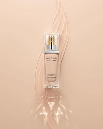 Estee Lauder Re-Nutriv liquid makeup bottle on a cream-colored background with light beige makeup swipe accent.