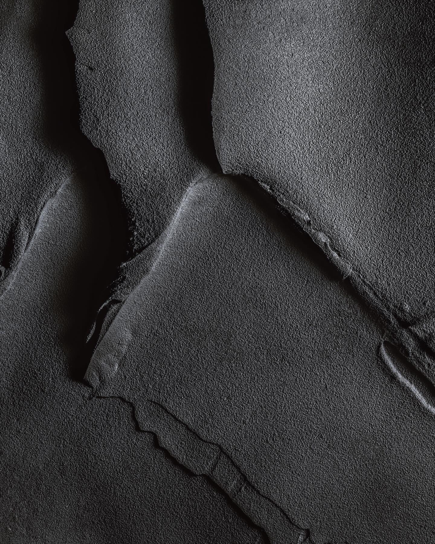 Abstract texture with ridges and crevices in tones of gray, creating a dramatic, monochrome landscape-like effect in a close-up view.
