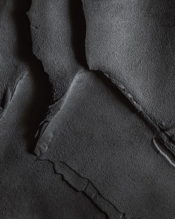 Abstract texture with ridges and crevices in tones of gray, creating a dramatic, monochrome landscape-like effect in a close-up view.