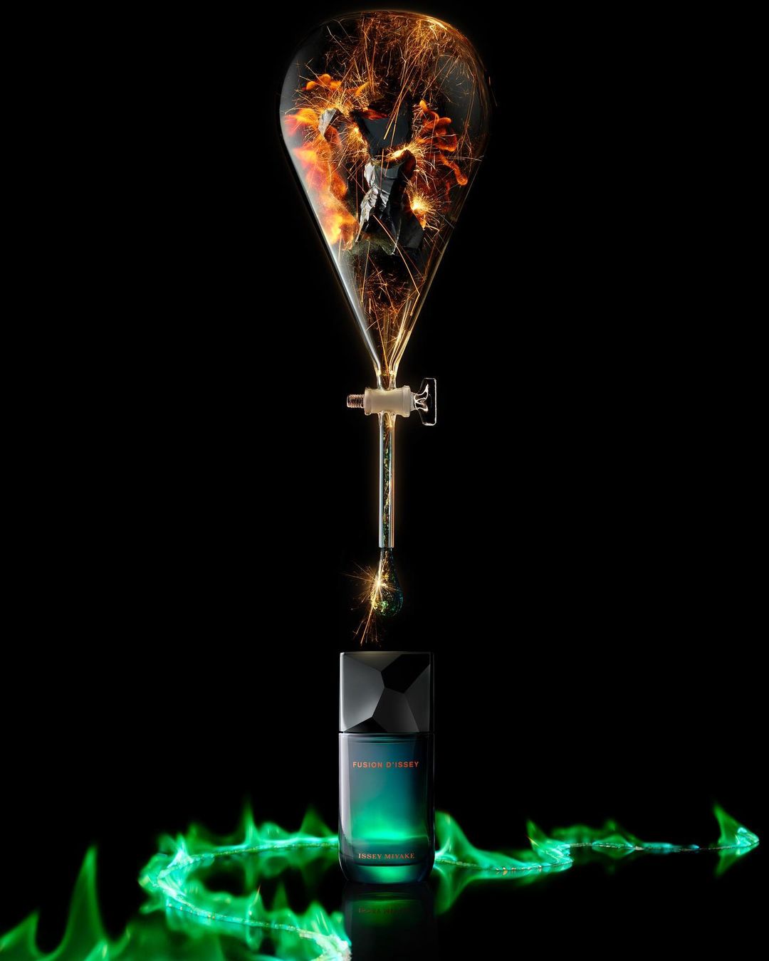 Perfume bottle on a reflective surface with simulated green flames, and a beaker with orange and black sparks against a black background.