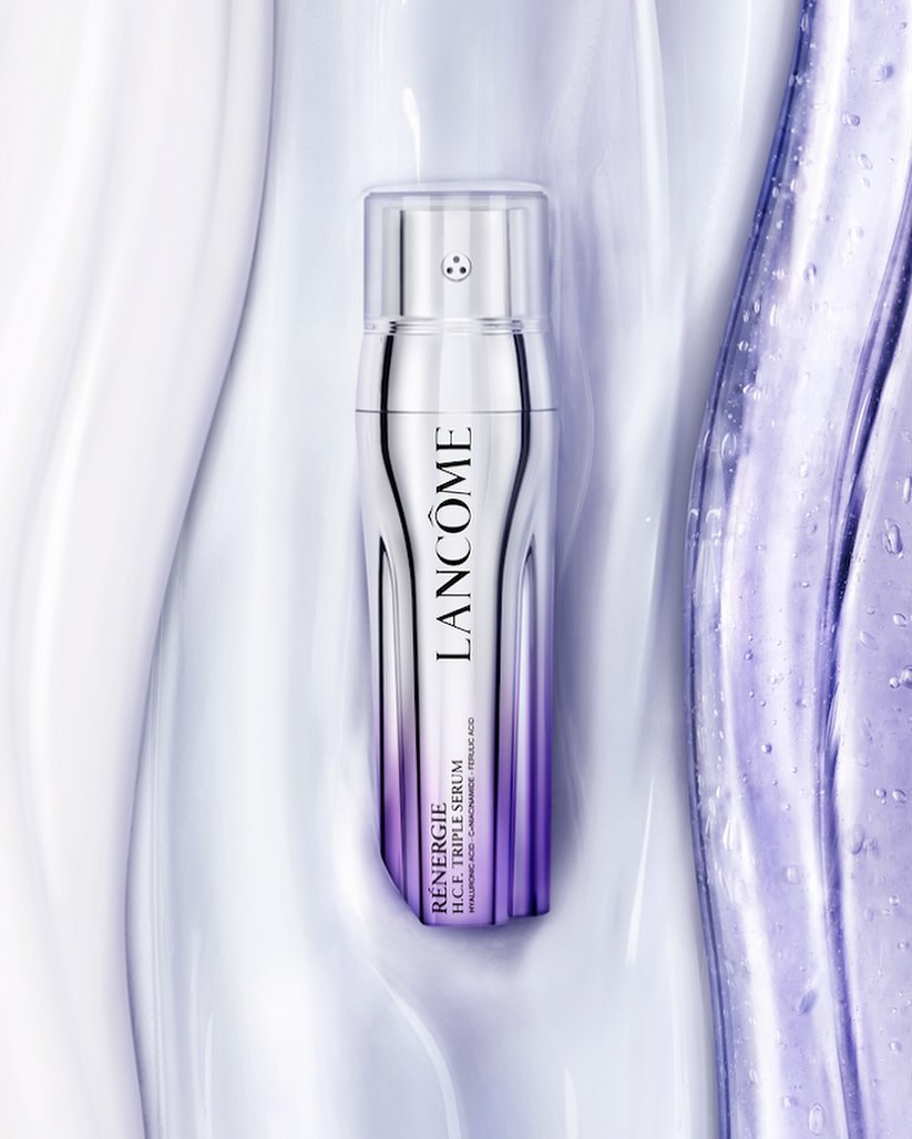 Lancôme Rénergie H.C.F. Triple Serum bottle displayed against a light, shiny surface, showcasing its silver and purple design.