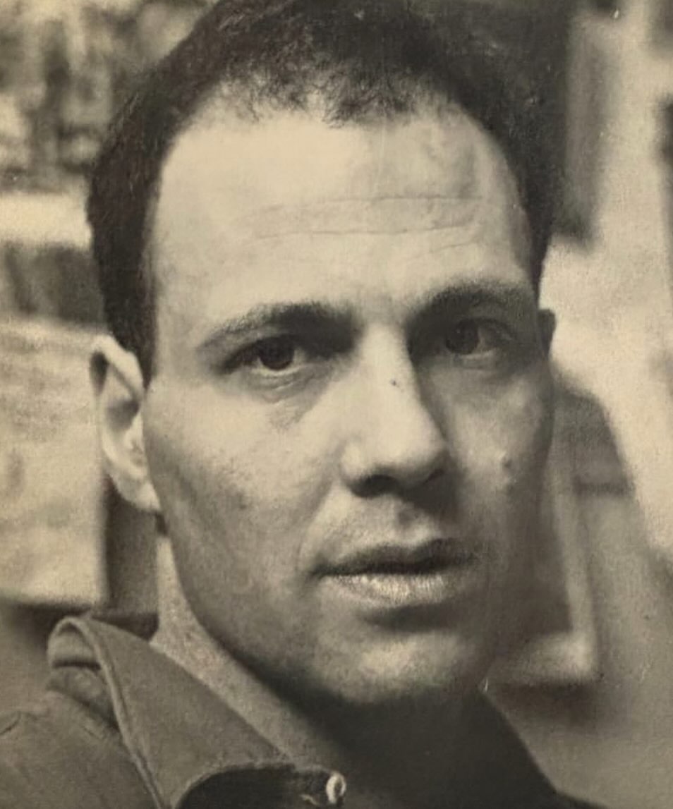 Portrait photograph of a man with short dark hair looking directly at the camera, captured by photographer Simon Watson.