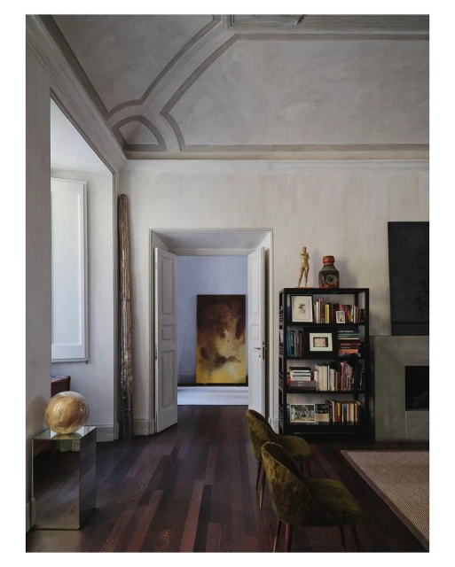 Interior view of a living room with hardwood floors, a fireplace, bookshelves, and decorative objects in a neutral color palette.