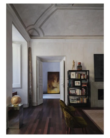 Interior view of a living room with hardwood floors, a fireplace, bookshelves, and decorative objects in a neutral color palette.