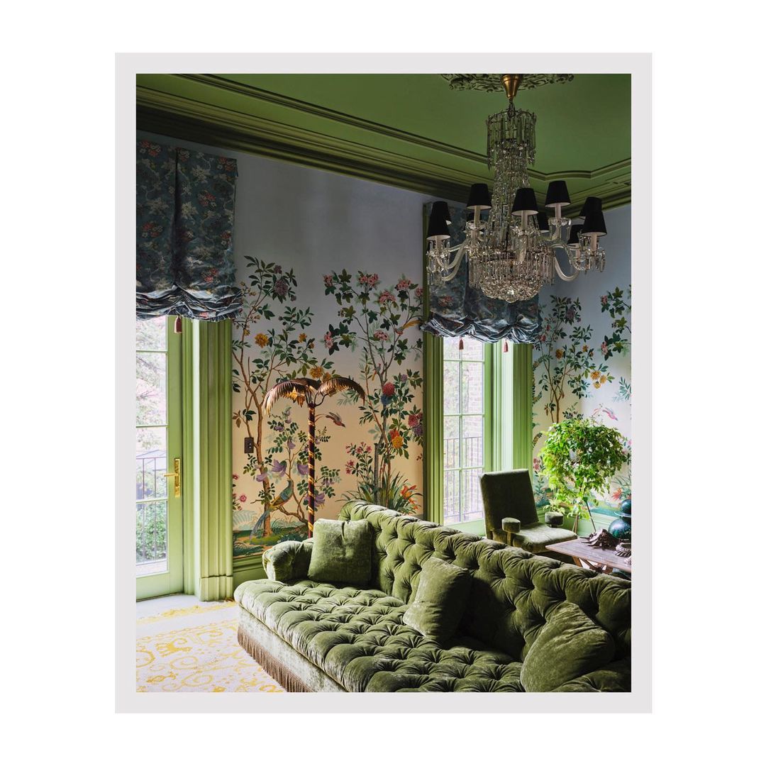 Interior view with green tufted sofa, floral wallpaper, crystal chandelier, and light green trim and accents in a well-lit room.