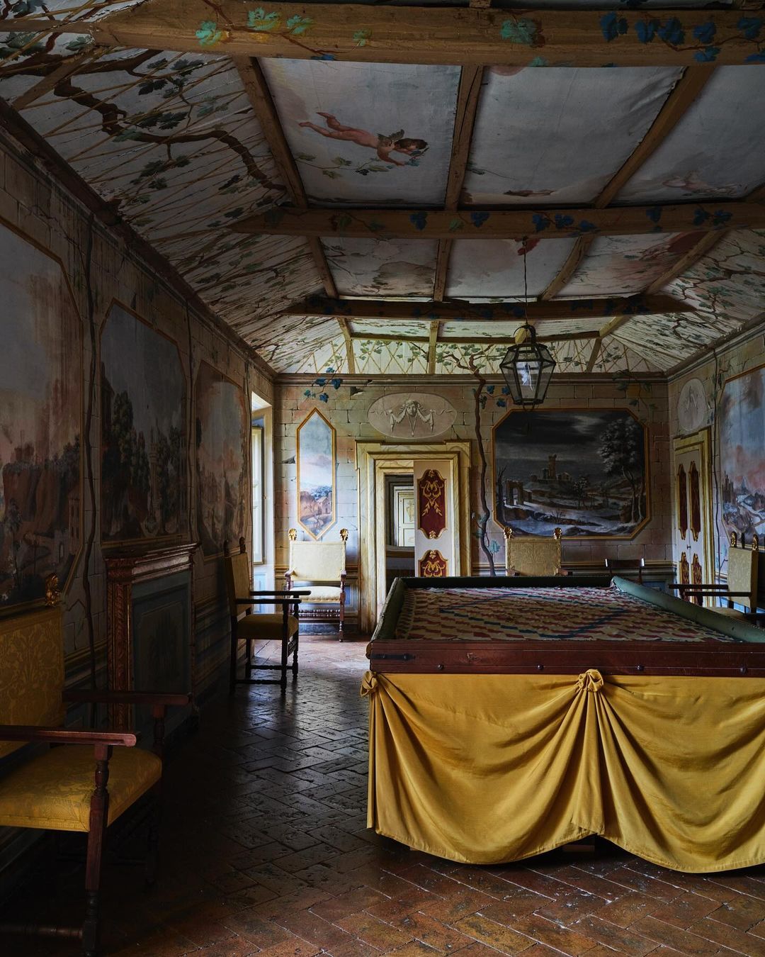 Ornate room features a billiard table, painted walls and ceiling, yellow drapes, antique furniture, and historic architectural details.