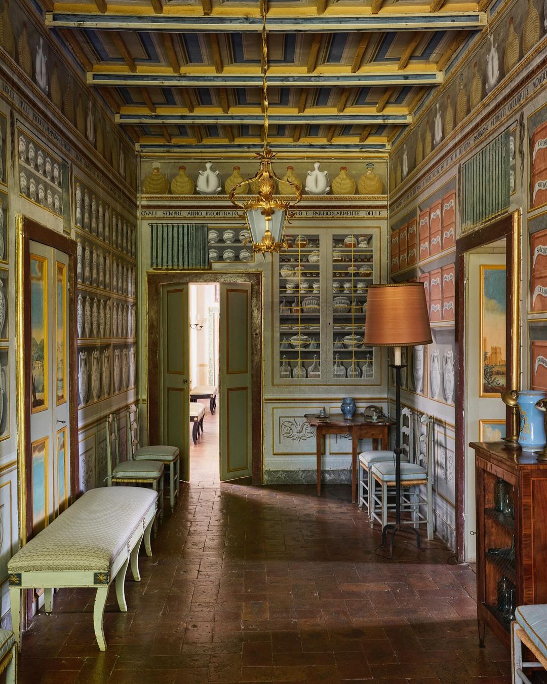 Ornate hallway with decorated walls, tile flooring, and vintage furniture creates a classic interior with architectural details.